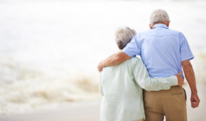 Elderly couple walking away from viewer arm in arm