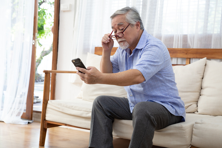 Older man looking at a smartphone held at a distance